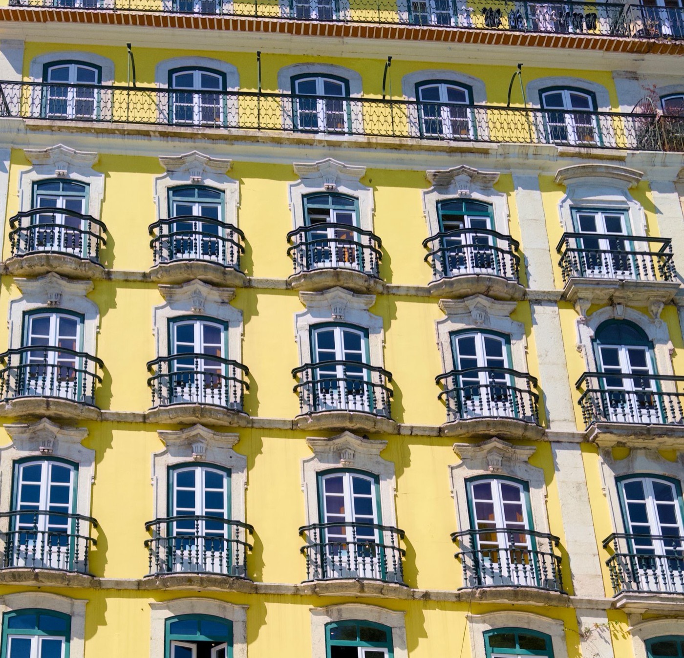 A yellow Lisbon apartment facade with balconies and quiet residential detail.