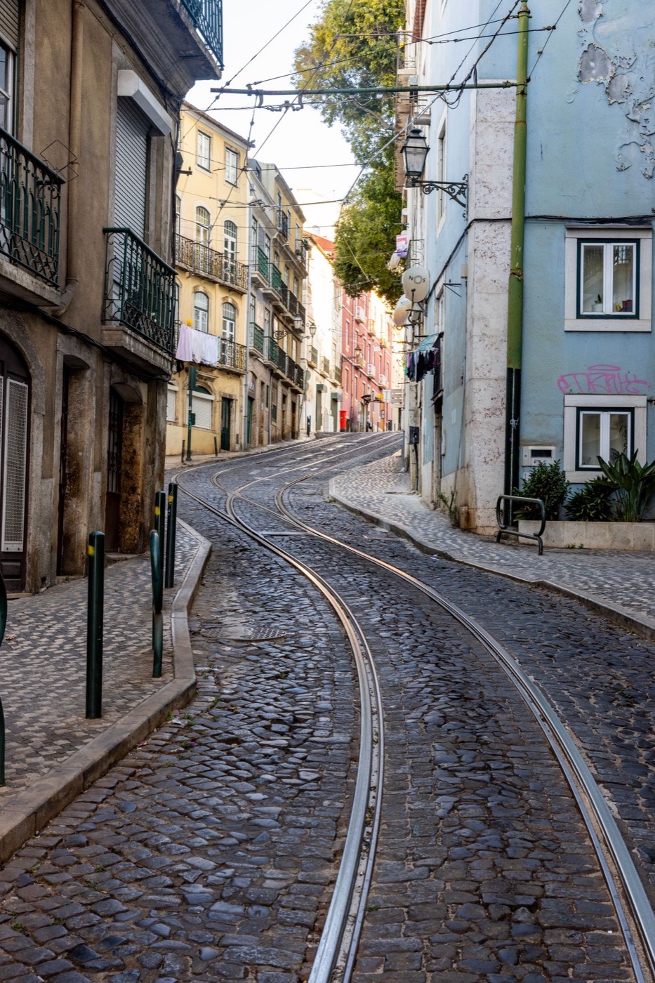 A residential Lisbon street with tram tracks and everyday apartment buildings.